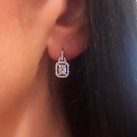 Close-up of a diamond earring worn by a person with dark hair.