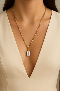 Gold necklace with a diamond pendant on a beige dress