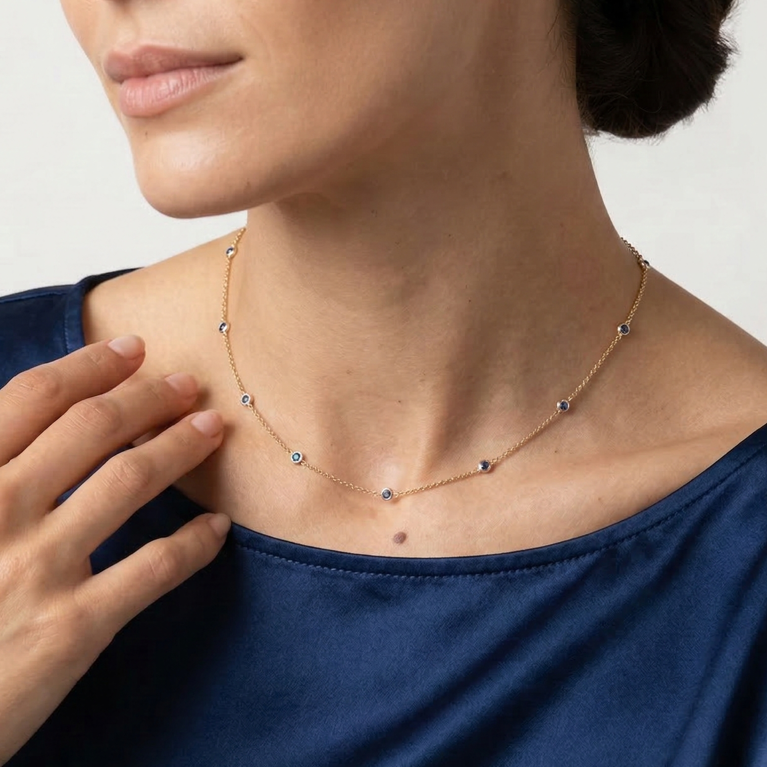 Woman wearing a delicate necklace with a plain background