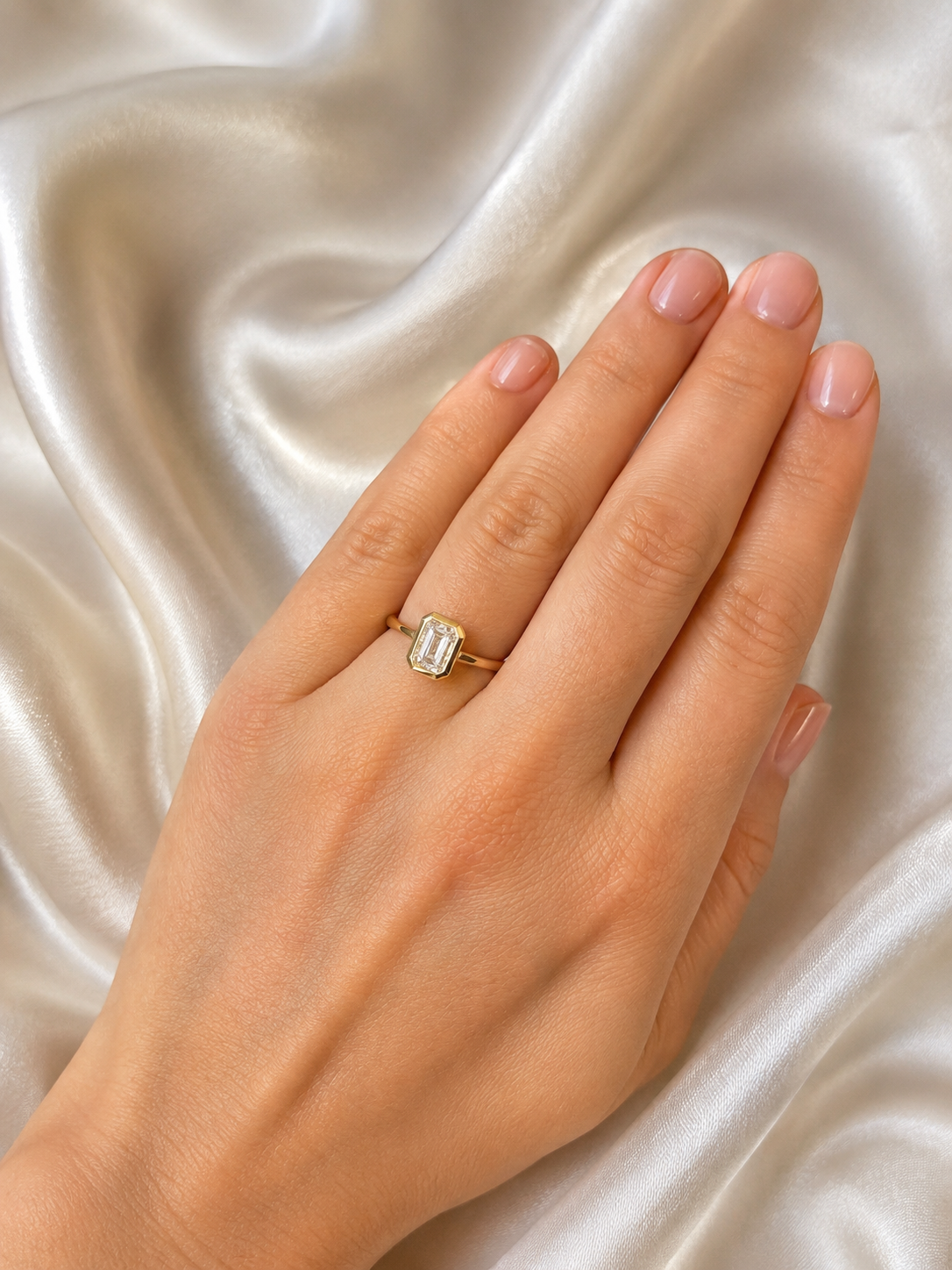 Emerald cut bezel diamond ring with 0.80ct, showcasing a sleek gold band and a sparkling central diamond.
