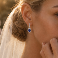 Close-up of a bride wearing a blue sapphire earring with a blurred outdoor background