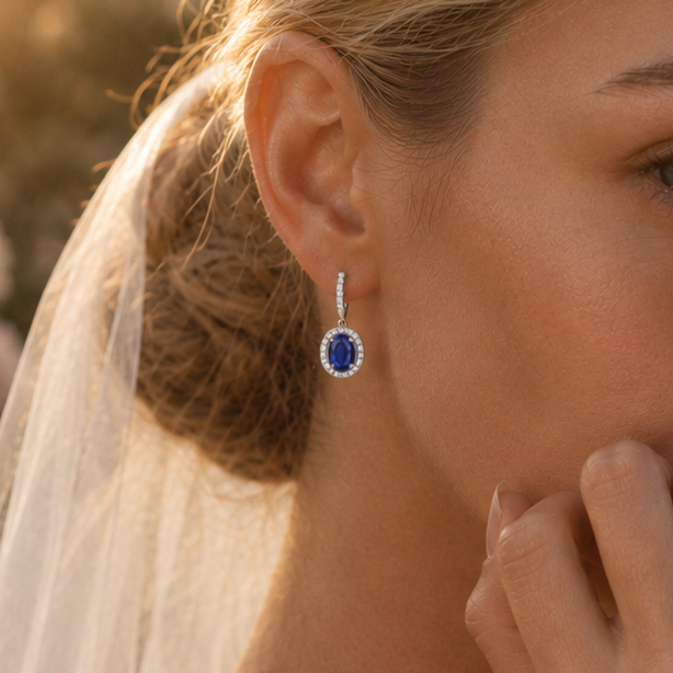Close-up of a bride wearing a blue sapphire earring with a blurred outdoor background