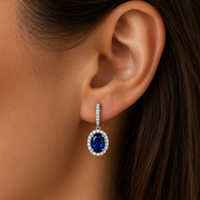 Close-up of an ear wearing a blue gemstone earring with a silver setting.