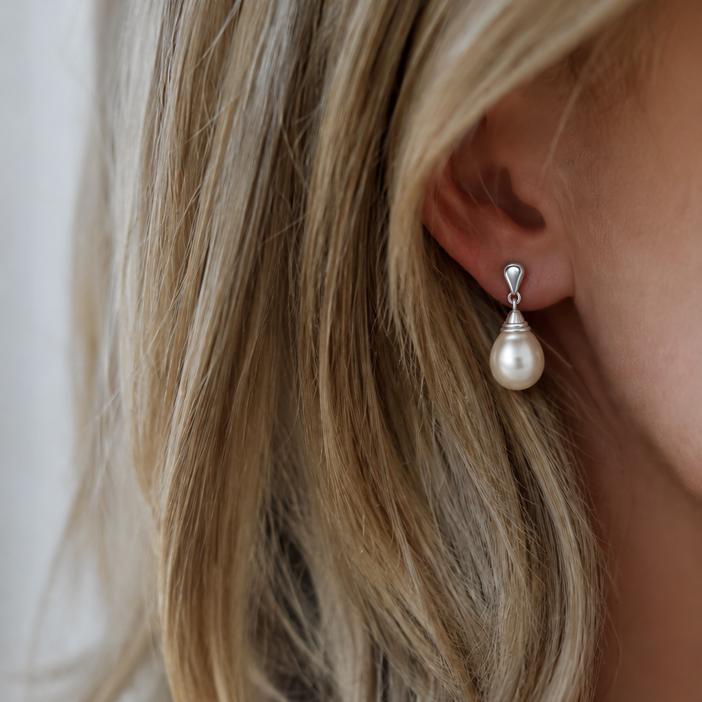 Pearl earring worn by a person with blonde hair.