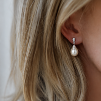 Pearl earring worn by a person with blonde hair.
