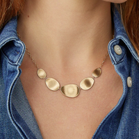 Gold necklace worn by a person with denim shirt