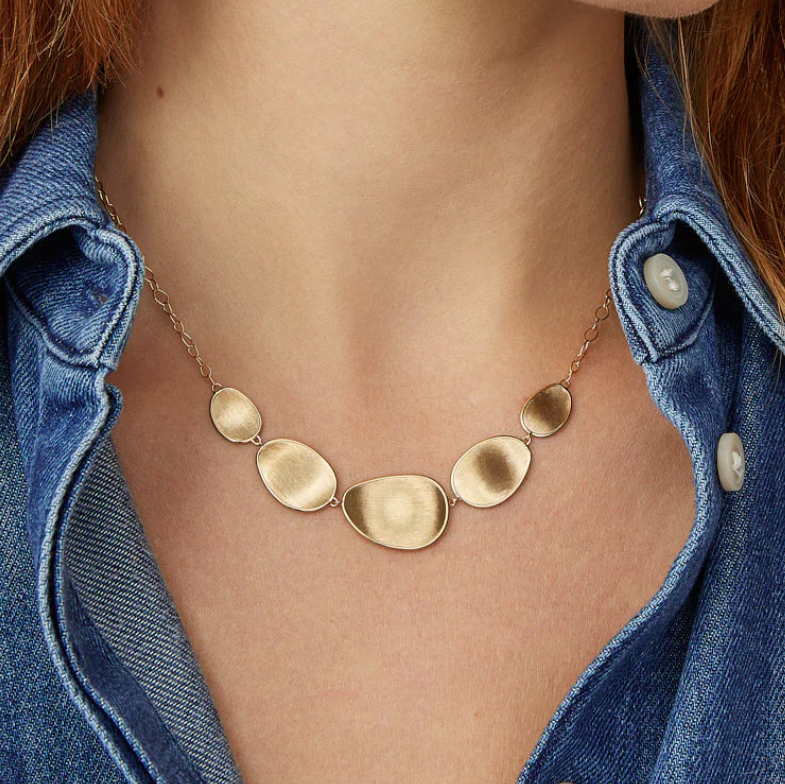 Gold necklace worn by a person with denim shirt