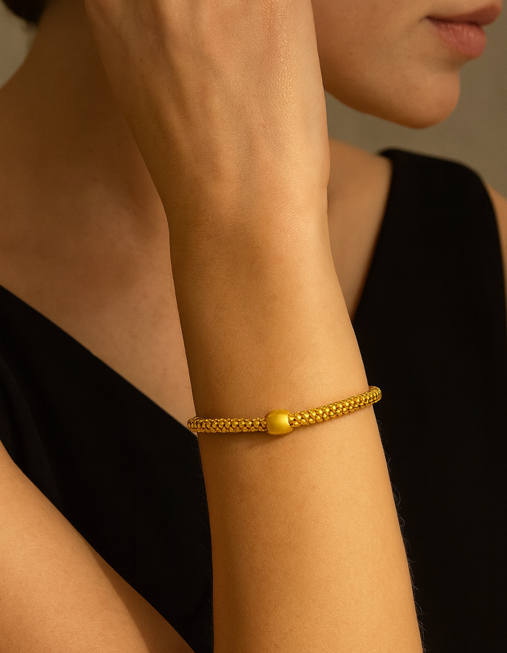 Gold bracelet on a person's wrist with a neutral background